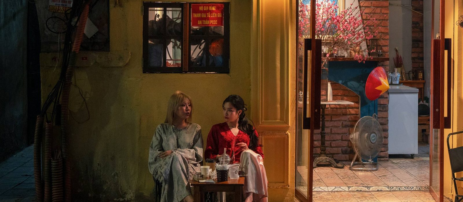 Two people meeting at a well-lit café on a public street at night
