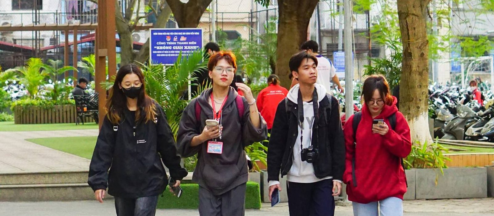 Four students walking together through a green campus