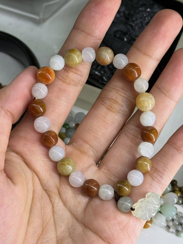A multicoloured jade bead bracelet held in an open palm