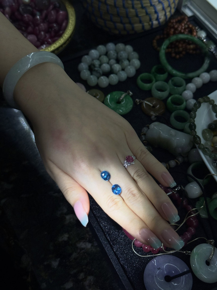 Two faceted blue gemstones resting on the back of a hand